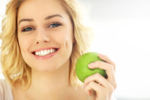 woman eating an apple to help with healthy teeth