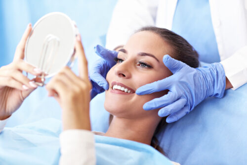 woman looking at teeth in mirror after getting a root canal