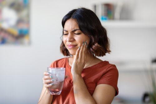 woman suffering from tooth sensitivity when drinking a drink
