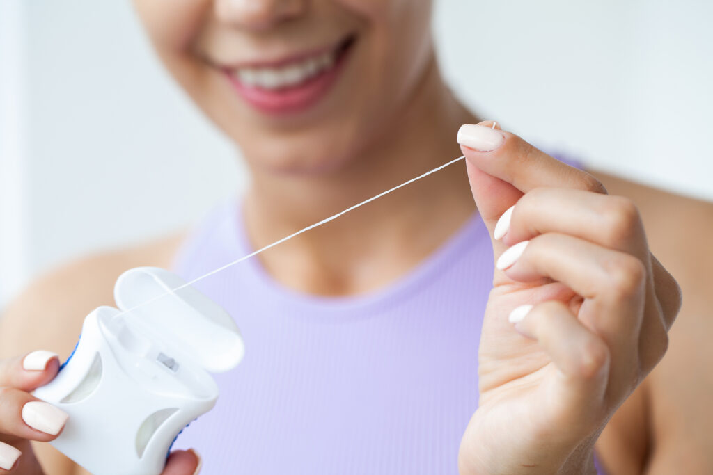 woman cleaning teeth with dental floss