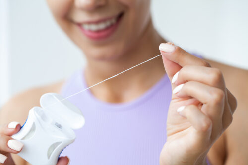 woman cleaning teeth with dental floss